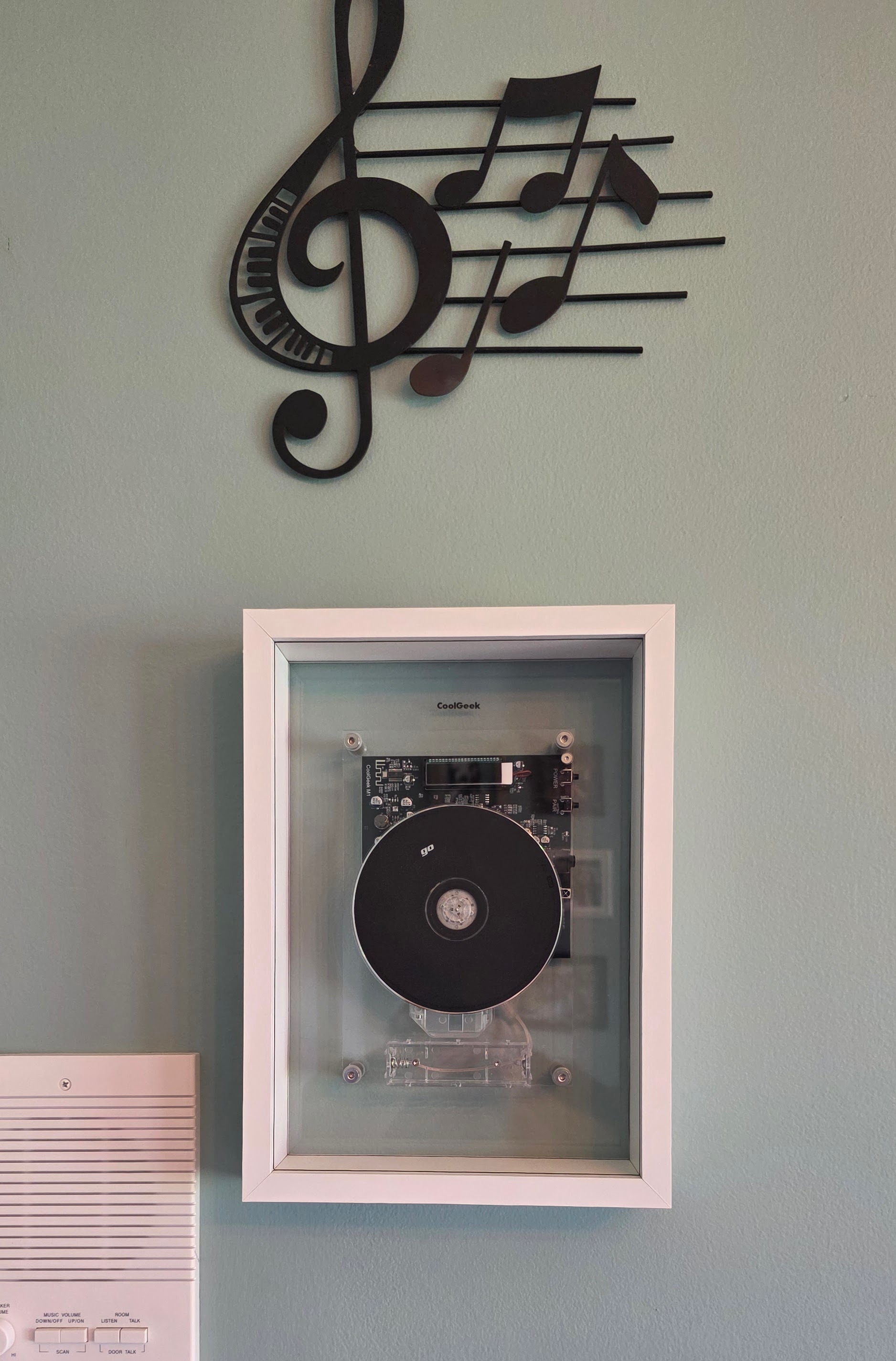 Wall-mounted CoolGeek M1 under music-staff art