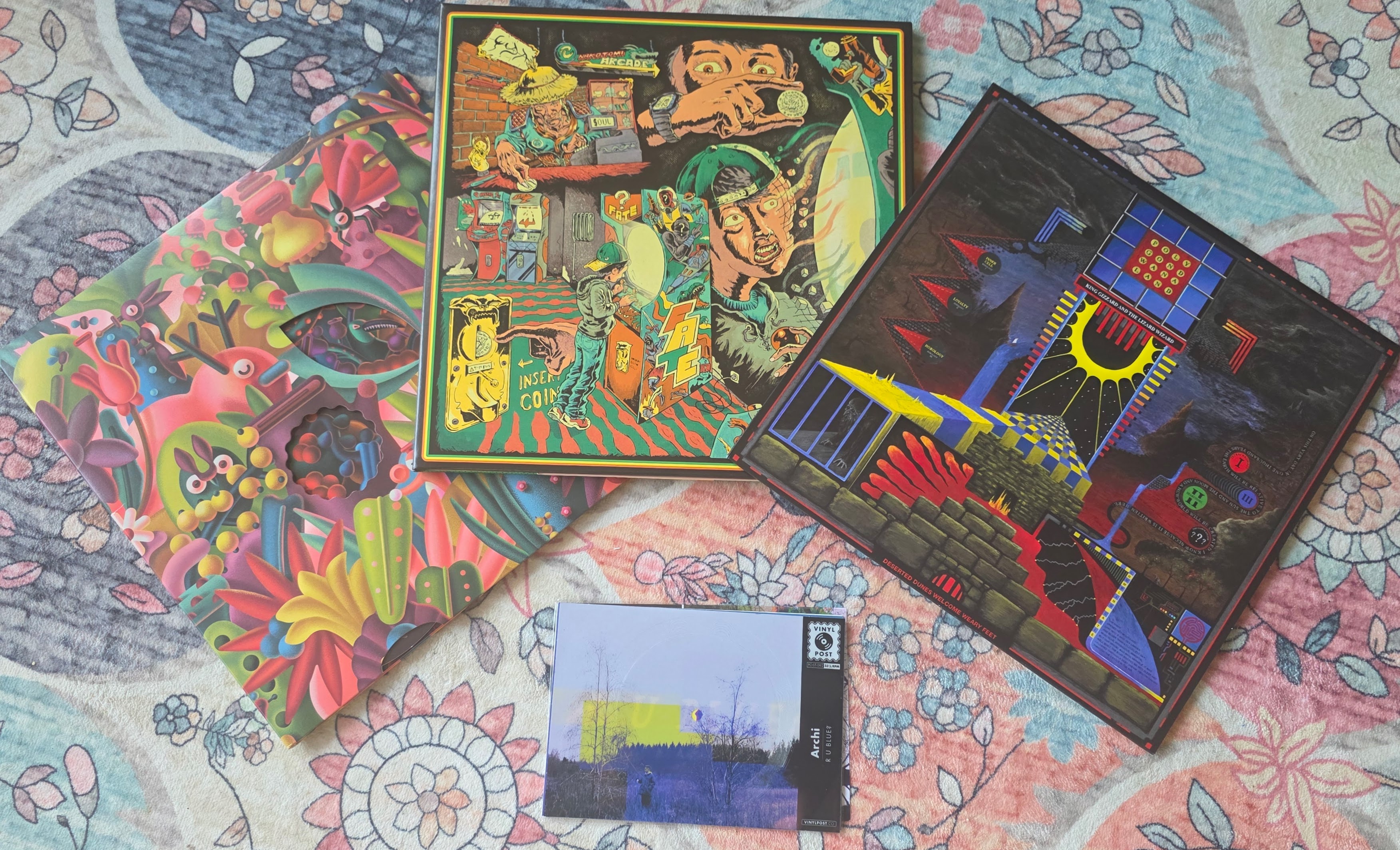 Vinyl Moon jackets and postcard single laid out on the parlor rug